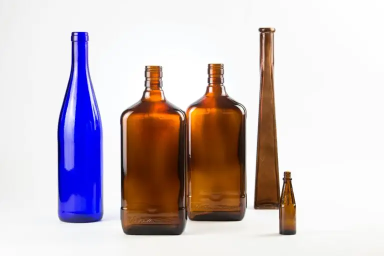 A collection of vintage glass bottles in various shapes and colors displayed against a white background.